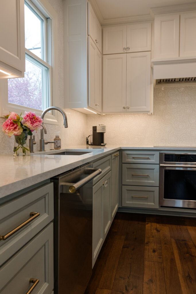 Remodeled kitchen with custom cabinetry, floral pattern backsplash tile, and undercabinet lighting.