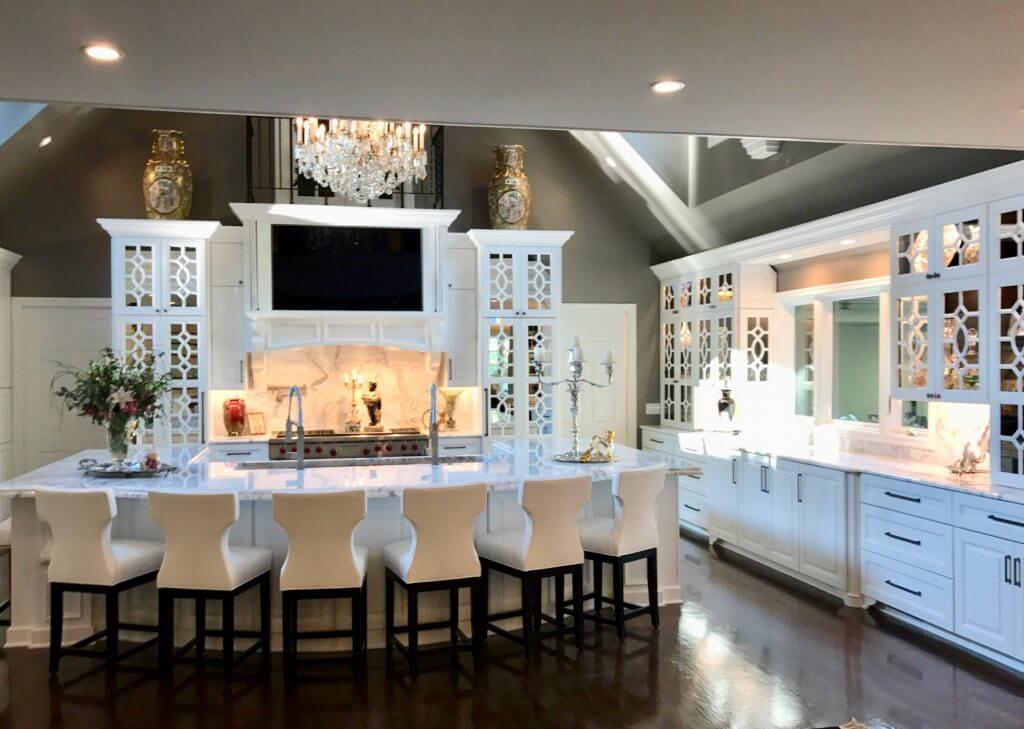 Kitchen remodel with custom wood product cabinets and mirrored cabinet doors featuring custom mullions and cabinet front appliances. Marble countertops, galley work station sink in the island, and dual faucets.