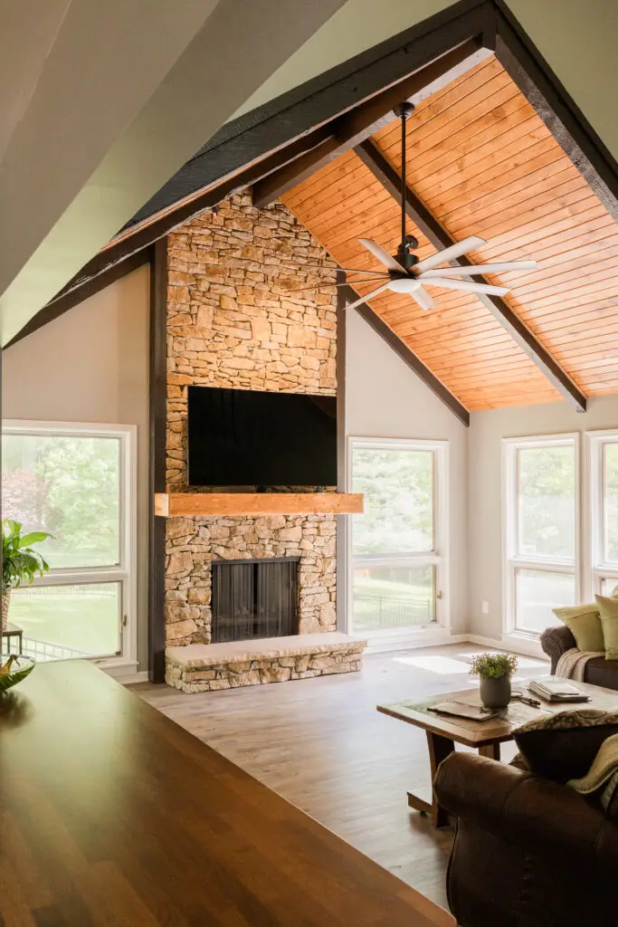 Family room with stone fireplace, large mantle, and carsided ceiling