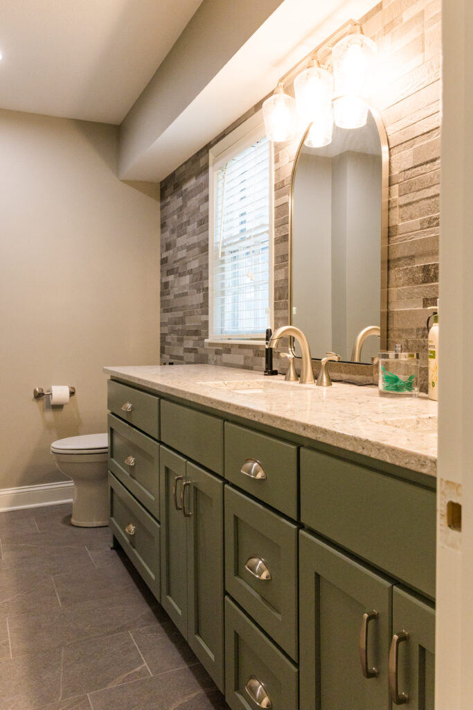 Primary bathroom with painted double vanity and stone accent wall
